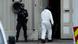 A police forensic passes a Norwegian policeman standing guards outside during investigations A police forensic passes a Norwegian policeman standing guards outside during investigations