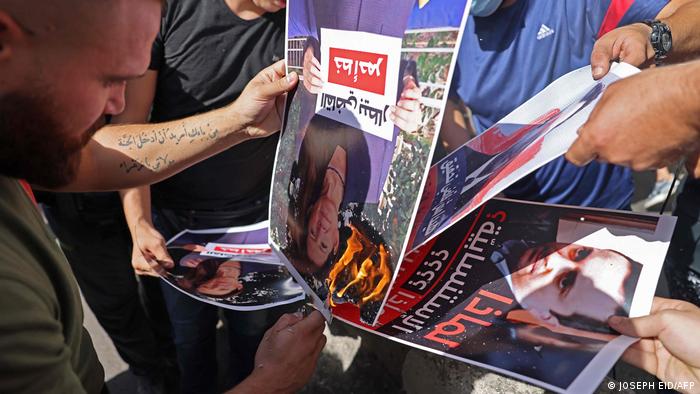 Seguidores de Hezbolá y Amal queman fotografías del juez Tarek Bitar en Beirut. (14.10.2021).
