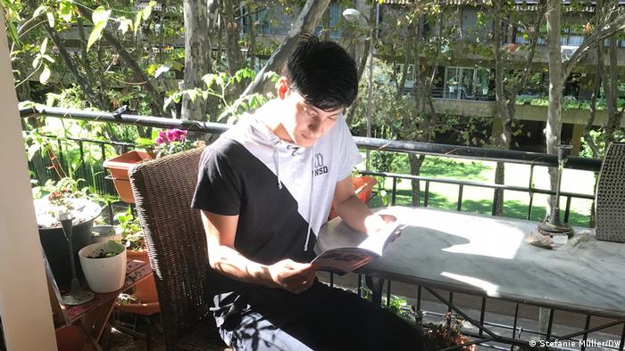 A picture of Ivan Rosero reading a book on the balcony of his parents appartment