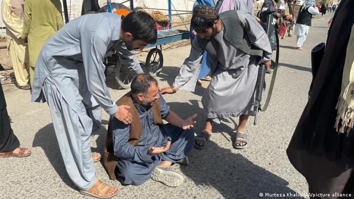 Dos hombres ayudan a otro tras el atentado con bomba en Kandhar, Afganistán. (15.10.2021).