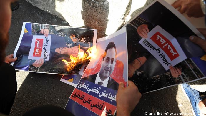 A poster with a picture of Judge Tarek Bitar who is investigating last year's deadly seaport blast, is set on fire by supporters of the Shiite Hezbollah and Amal groups