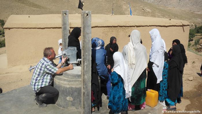Stefan Recker kneels while speaking to a group of women and girls in Afghanistan