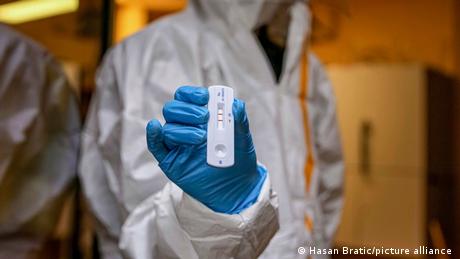 A laboratory technician holds up a positive rapid antigen test
