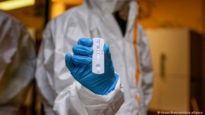 A laboratory technician holds up a positive rapid antigen test