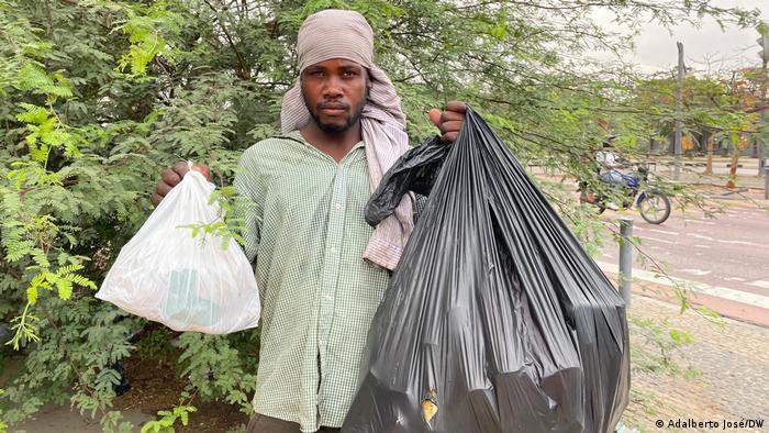 Jovem angolano mostra saco de lixo