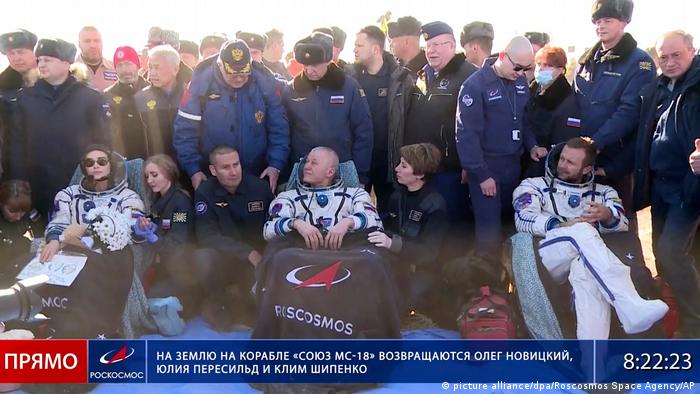 Atriz Yulia Peresild, cosmonauta Oleg Novitsky e diretor Klim Shipenko assistidos por pessoal da Roscosmos após pouso