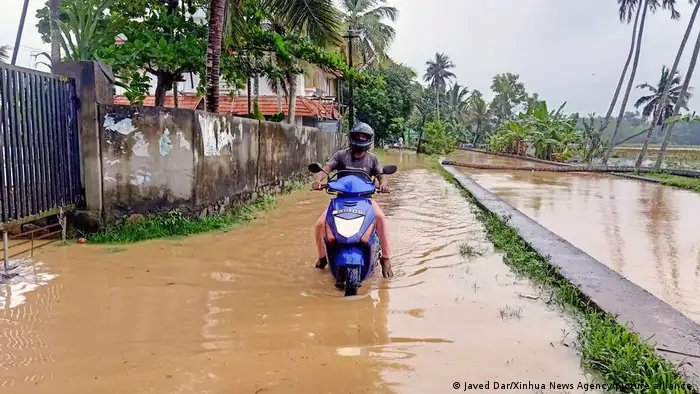 a person drives a motorcycle through a waterlogged street