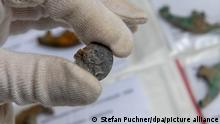 Eine Mitarbeiterin der Stadtarchäologie hält eine Münze, auf der Kaiser Augustus abgebildet ist. Diese gehört zu Ausgrabungsfunden aus der Römerzeit, die nach Angaben der Stadt belegen, dass es sich bei dem vor mehr als 2000 Jahren gegründeten Augsburger Militärlager um den ältesten römischen Stützpunkt im heutigen Bayern handelt.