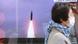 A woman walks past a TV screen showing North Korea fired missiles in a news program in Tokyo A woman walks past a TV screen showing North Korea fired missiles in a news program in Tokyo