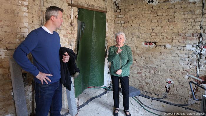 María y Thomas Dunkel están en el primer piso de su casa con solo paredes de ladrillo visto.