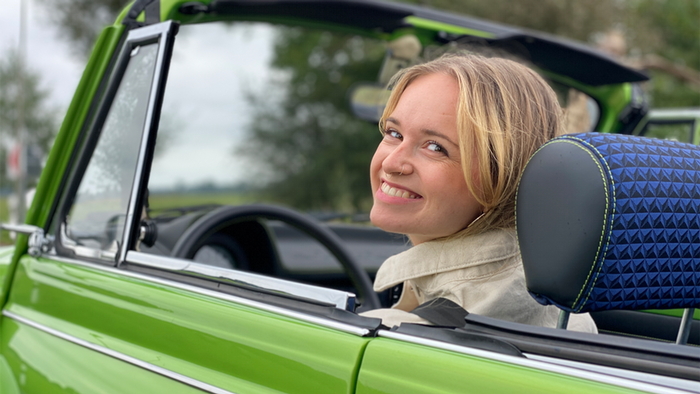 Woman at wheel of a green car, smiling