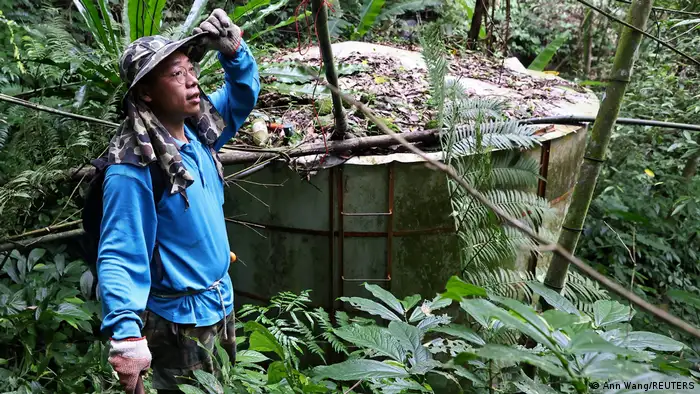 Plantation owner Chien Shun-yih standing next to his self-built water storage tank