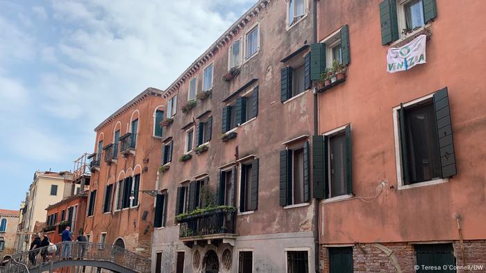 Casas antigas em Veneza. Faixa SOS Venezia pende de uma janela