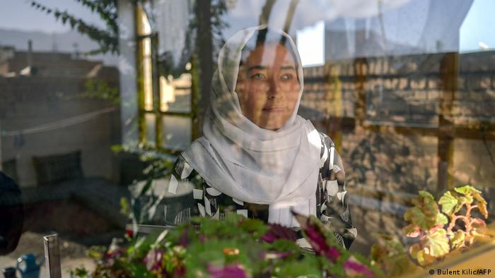 Eine junge Frau in Afghanistan steht am Fenster