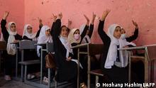 This picture taken on September 20, 2021, shows young female students girls raising their hands during a class at Gawhar Shad Begum school in Herat. (Photo by Hoshang Hashimi / AFP)