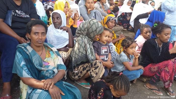 A group of women and children sit and wait