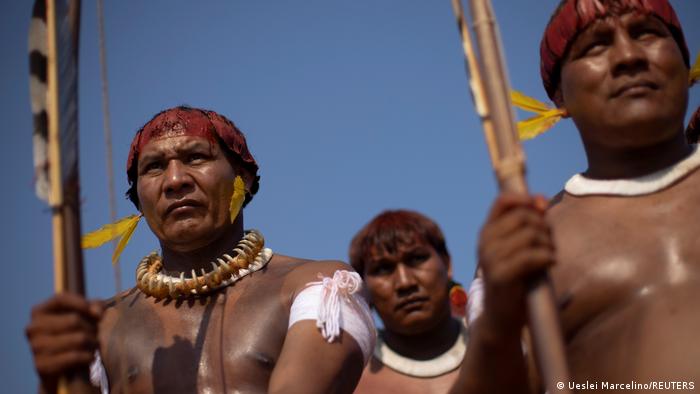 Foto em close de três homens indígenas com os rostos pintados 