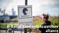 Un empleado descuelga un afiche sobre la obligación de usar mascarilla en el especio público en Hamburgo, Alemania.