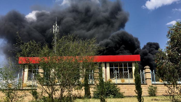 Black smokes billows behind a building
