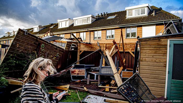 Une femme regarde son téléphone portable alors qu'elle se tient devant un patio détruit à Barendrecht, aux Pays-Bas