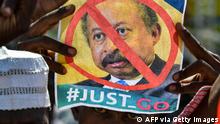 A Sudanese demonstrator raises a picture bearing a crossed out face of Prime Minister Abdalla Hamdok, during a rally in front the presidential palace in the capital Khartoum, demanding a return to military rule, on October 21, 2021. - Supporters of Sudan's transitional government took to the streets of the capital today as rival demonstrators kept up a sit-in demanding a return to military rule. The mainstream faction backs the transition to civilian rule, while supporters of the breakaway faction are demanding the military take over. (Photo by AFP) (Photo by -/AFP via Getty Images)
