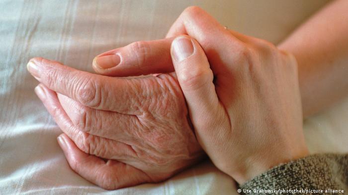 A hand of a younger person comforting an older one