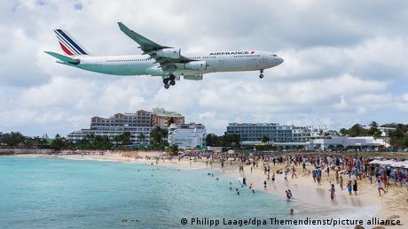 An airplane flies over the beach at St. Martin in the Caribbean. 