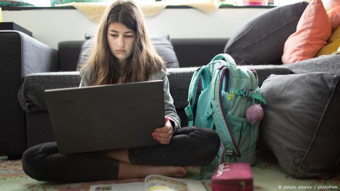 Una ragazza che usa il suo laptop davanti al divano a scuola a casa