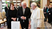 This handout picture taken and released on October 25, 2021, shows German President Frank-Walter Steinmeier (C) and his wife Elke Buedenbender (L) exchanging gifts with pope Francis during a meeting in the Vatican. (Photo by Handout / various sources / AFP) / RESTRICTED TO EDITORIAL USE - MANDATORY CREDIT AFP PHOTO / VATICAN MEDIA - NO MARKETING - NO ADVERTISING CAMPAIGNS - DISTRIBUTED AS A SERVICE TO CLIENTS