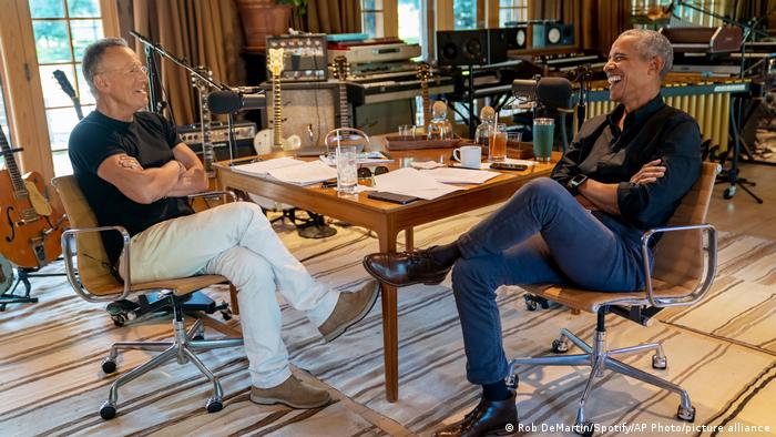 Bruce Springsteen und Barack Obama sitzen an einem Tisch, vor ihnen Mikrofone.