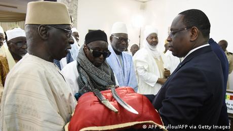 Senegal President Macky Sall (R) receives the sword El Hadj on a red cushion during a ceremony with various African dignitaries.
