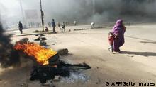 A Sudanese woman and child walk past as protesters burn tyres to block a road in 60th Street in the capital Khartoum, to denounce overnight detentions by the army of members of Sudan's government, on October 25, 2021. - Armed forces detained Sudan's Prime Minister over his refusal to support their coup, the information ministry said, after weeks of tensions between military and civilian figures who shared power since the ouster of autocrat Omar al-Bashir. (Photo by AFP) (Photo by -/AFP via Getty Images)