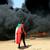 A person wearing a Sudan's flag stand in front of a burning pile of tyres during a protest against prospect of military rule in Khartoum