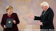 German Chancellor Angela Merkel, left receives her certificate of dismissal from German President Frank-Walter Steinmeier in Berlin, Tuesday, Oct. 26, 2021. Merkel stays in office until a successor is elected. (AP Photo/Markus Schreiber)
