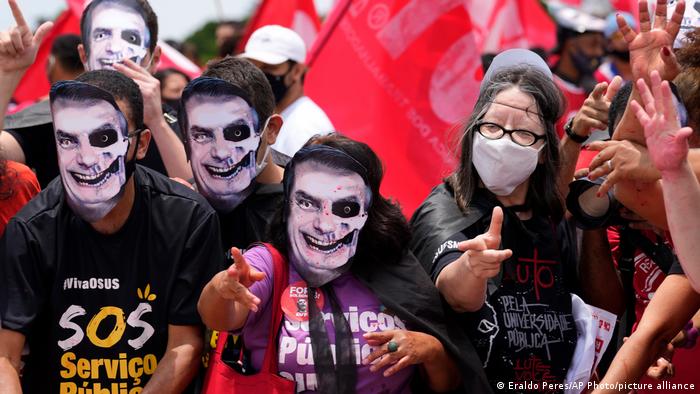 Демонстранты в масках с лицом Болсонару протестуют против политики властей по борьбе с ковидом