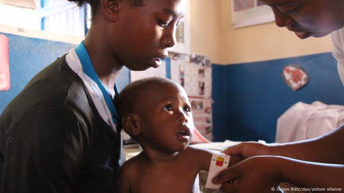 A social worker measures the circumfence of the arm of a small child.