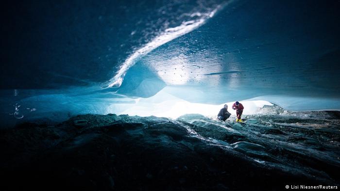 Two people explore a natural glacier cavity of the Jamtalferner glacier near Galtuer, Austria