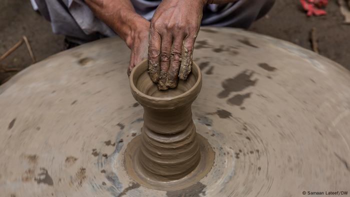 A potter molds the clay on a potter's wheel