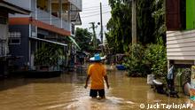 A man wades through floodwaters in a neighbourhood in Ayutthaya on October 4, 2021, after tropical storm Dianmu caused flooding in 31 provinces across the country. (Photo by Jack TAYLOR / AFP)