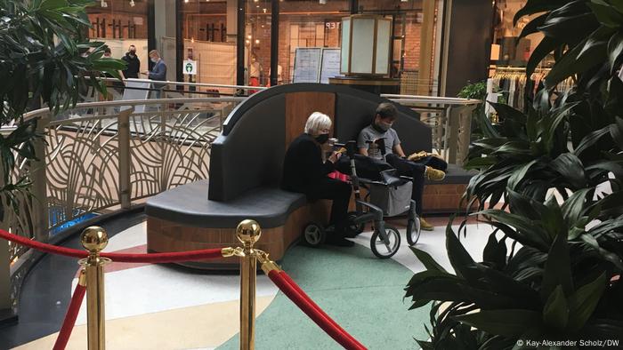 Une femme âgée et un jeune homme se reposant dans le centre commercial