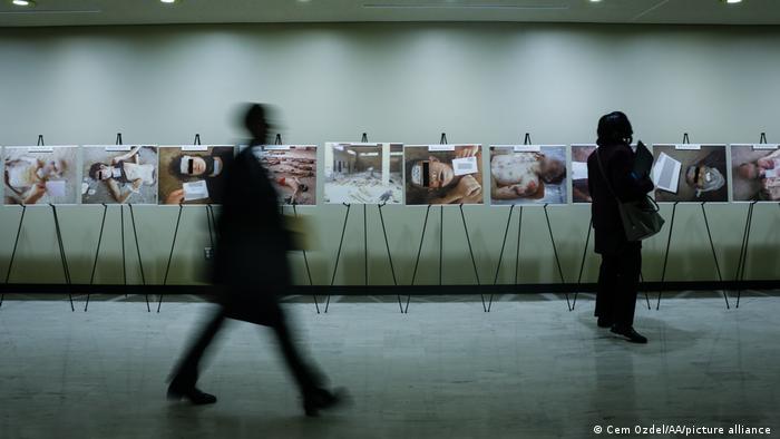 Visitors to the UN in New York pass by images of victims of torture by Syrian regime forces