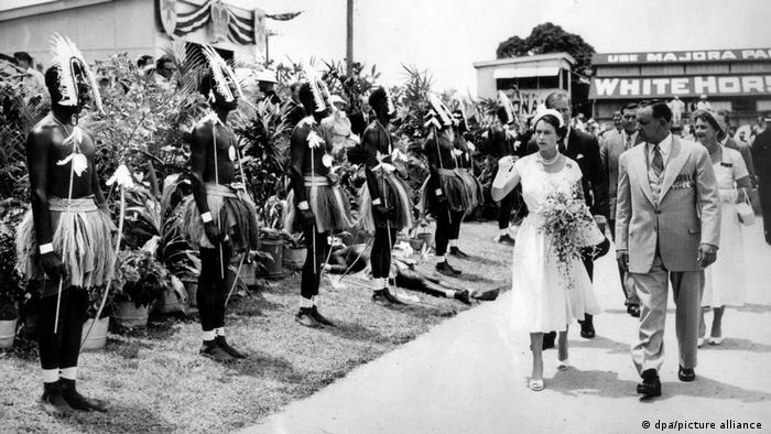 Queen Elizabeth II and her entourage walk past Aborigine honor guards. 