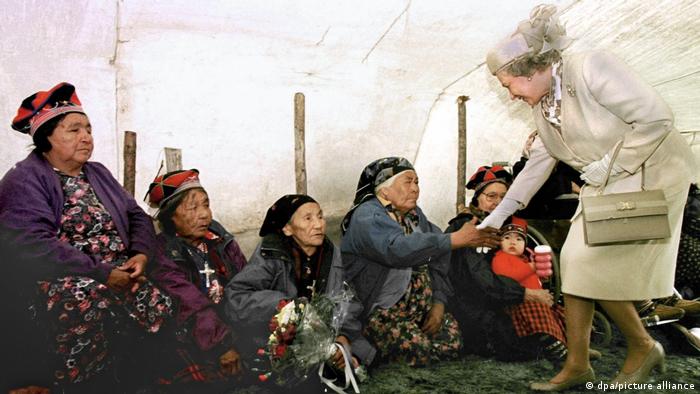 Queen Elizabeth stoops down to shake the hands of Inuit women in Labrador, Canada.