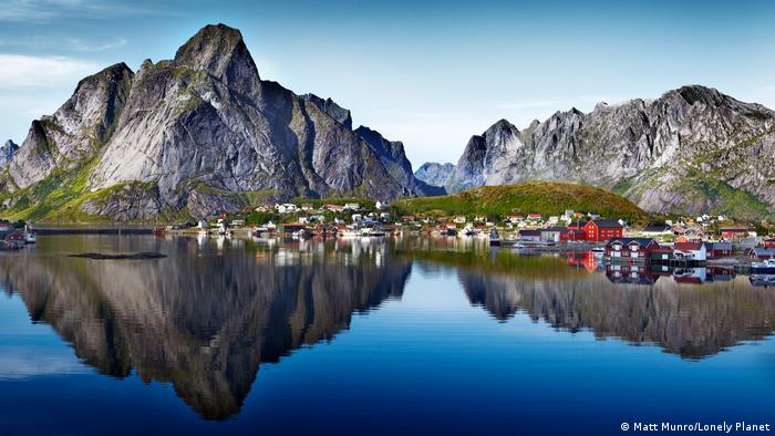 View across a lake of a small village and surrounding mountains in Norway