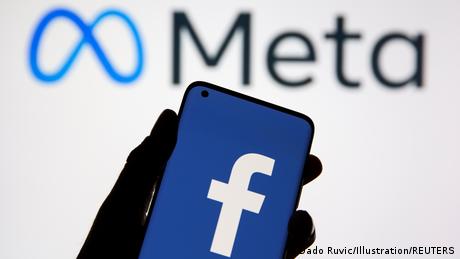 A smartphone with Facebook's in front of its parent company Meta's logo