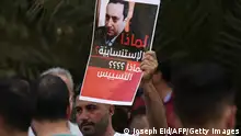 A supporter of Hezbollah and the Amal movements carries a portrait of Judge Tarek Bitar, the Beirut blast lead investigator, near the Justice Palace in the capital Beirut on October 14, 2021, during a gathering to demand his dismissal. (Photo by JOSEPH EID / AFP) (Photo by JOSEPH EID/AFP via Getty Images)