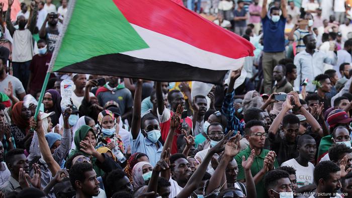 Menschenmenge protestiert und schwenkt eine sudanesische Flagge