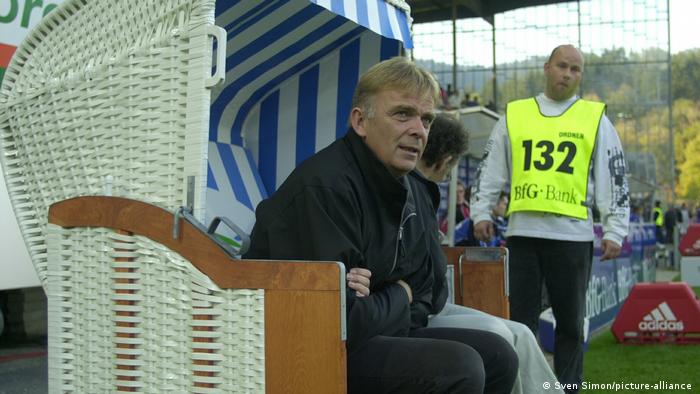 Freiburg's former coach Volker Finke watches his team from a German wicker beach chair 