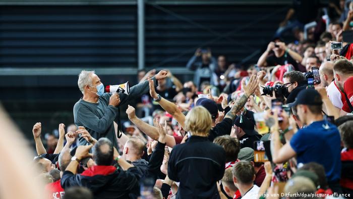Christian Streich holding a megaphone addressing fans after Freiburg's match against Augsburg in the Bundesliga 