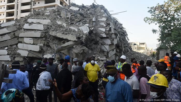 Menschen stehen um die Trümmer eines eingestürzten Hochhauses in Lagos, Nigeria 